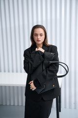 Girl model in stylish clothes with bag posing in studio