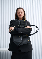Girl model in stylish clothes with bag posing in studio