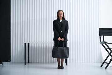 Girl model in stylish clothes with bag posing in studio