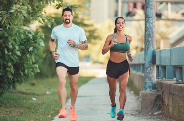 Young fitness couple running on a city on summer day