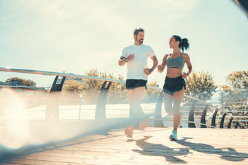 Young fitness couple running on a city on summer day