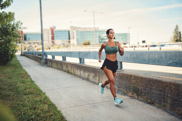 Happy sporty woman jogging outdoors in urban scene
