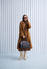 Girl model in stylish clothes with bag posing in studio