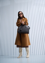 Girl model in stylish clothes with bag posing in studio