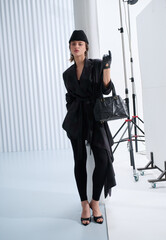 Girl model in stylish clothes with bag posing in studio