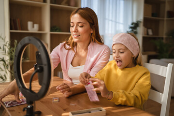 Mother and daughter applying makeup together for video blog recording