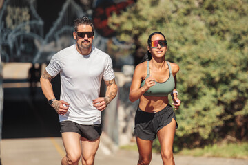 Young fitness couple running on a city on summer day