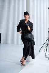 Girl model in stylish clothes with bag posing in studio