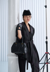 Girl model in stylish clothes with bag posing in studio
