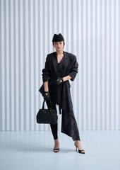Girl model in stylish clothes with bag posing in studio