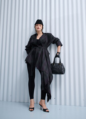 Girl model in stylish clothes with bag posing in studio