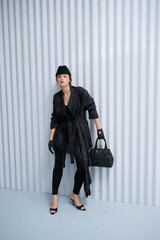 Girl model in stylish clothes with bag posing in studio