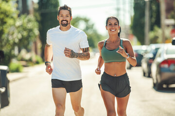 Young fitness couple running on a city on summer day