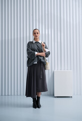 Girl model in stylish clothes with bag posing in studio