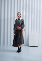 Girl model in stylish clothes with bag posing in studio