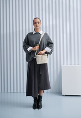 Girl model in stylish clothes with bag posing in studio
