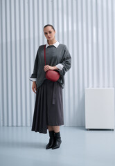 Girl model in stylish clothes with bag posing in studio