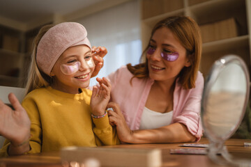 Mother and daughter applying eye patches and having fun at home