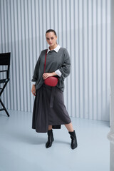 Girl model in stylish clothes with bag posing in studio