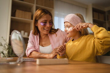 Mother and daughter applying eye patches and having fun at home