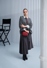 Girl model in stylish clothes with bag posing in studio