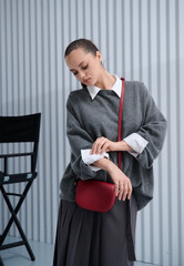 Girl model in stylish clothes with bag posing in studio