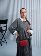 Girl model in stylish clothes with bag posing in studio