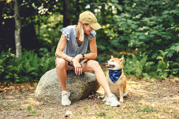 Fototapeta premium Happy woman with her Shiba Inu dog in the forest on summer season