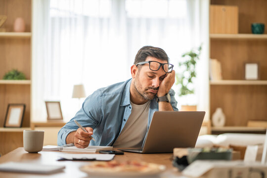 Tired businessman sleeping at desk while working from home - Powered by Adobe