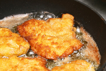 Fried chicken cutlet in pan. Golden crispy schnitzel. Hot oil cooking process. Traditional homemade dinner. Freshly prepared meal. Rustic food detail.
