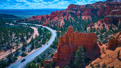 Obraz premium Aerial Red Canyon Road and Red Rock Formations with Pine Trees Utah