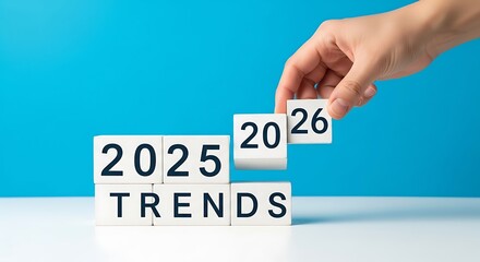 Hand arranging blocks to show 2025 and 2026 trends, future planning concept