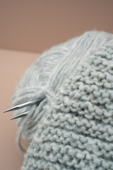 Flat lay composition of a grey yarn wrench ball with knitting needles on a beige cream background. Perfect for themes related to knitting, crochet, handmade crafts, textile design, and neutral-toned c