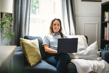 woman sitting surfing the internet on a laptop computer on a sofa at home
