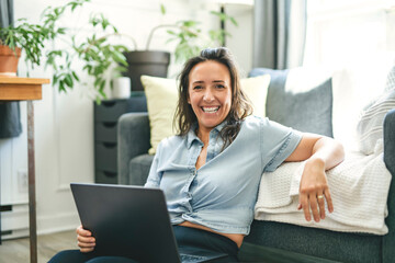 woman sitting surfing the internet on a laptop computer on a sofa at home