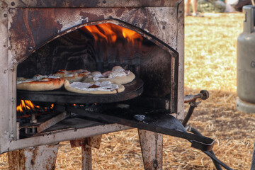 Druze-style pita breads baking in a taboon oven with fire