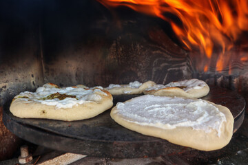 Druze-style pita breads baking in a taboon oven with fire