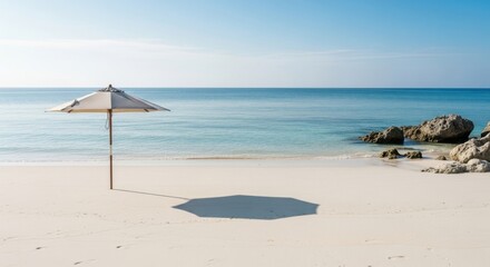 Fototapeta premium Serene Beach Scene With Umbrella Casting Shadow Under Clear Blue Sky