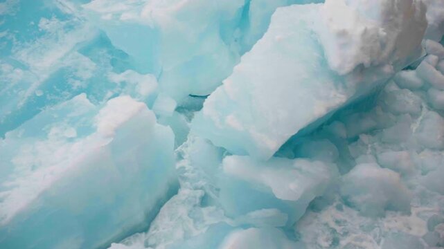 Drifting slabs of pale blue sea ice breaking apart into jagged chunks, revealing layered textures and frosty edges as floating floes collide and grind across turquoise water