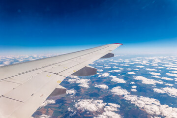 View from the airplane window at a beautiful cloudy sky and the airplane wing