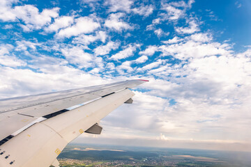 Obraz premium View of airplane wing, blue skies and green land during landing. Airplane window view.