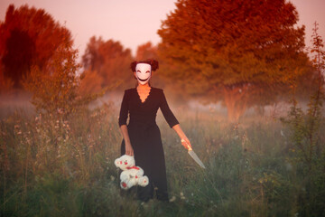 Creepy masked woman holding teddy bear with kitchen knife