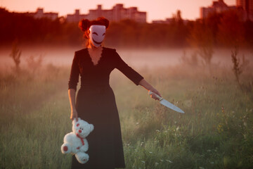 Creepy masked woman holding teddy bear with kitchen knife