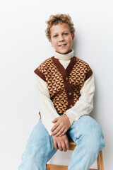 Authentic portrait of a school aged boy in a patterned knit vest and cozy sweater, captured in a...