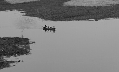 Traditional wooden boat with local people rowing on calm Irrawaddy River near Bagan at sunrise, Myanmar 2019