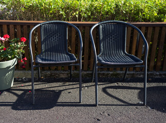 Two empty chairs in the park infront of a hedge