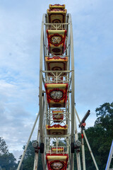Ferris wheel with colorful cabins against cloudy sky at a fairground in summer
