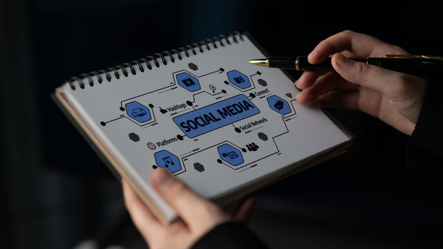 A close-up image featuring hands holding a notepad with a detailed social media concept illustration, emphasizing connections, icons, and networking strategies for digital communication. Tessel
