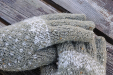 Hands in knitted woolen gloves on a wooden background. Knitting clothes by hand.
