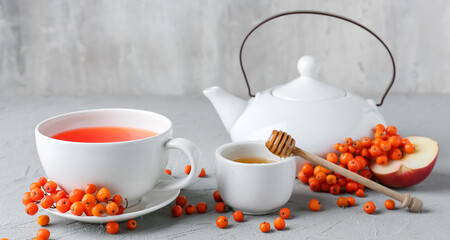 Composition with cup of tasty rowan tea, honey and berries on grunge background